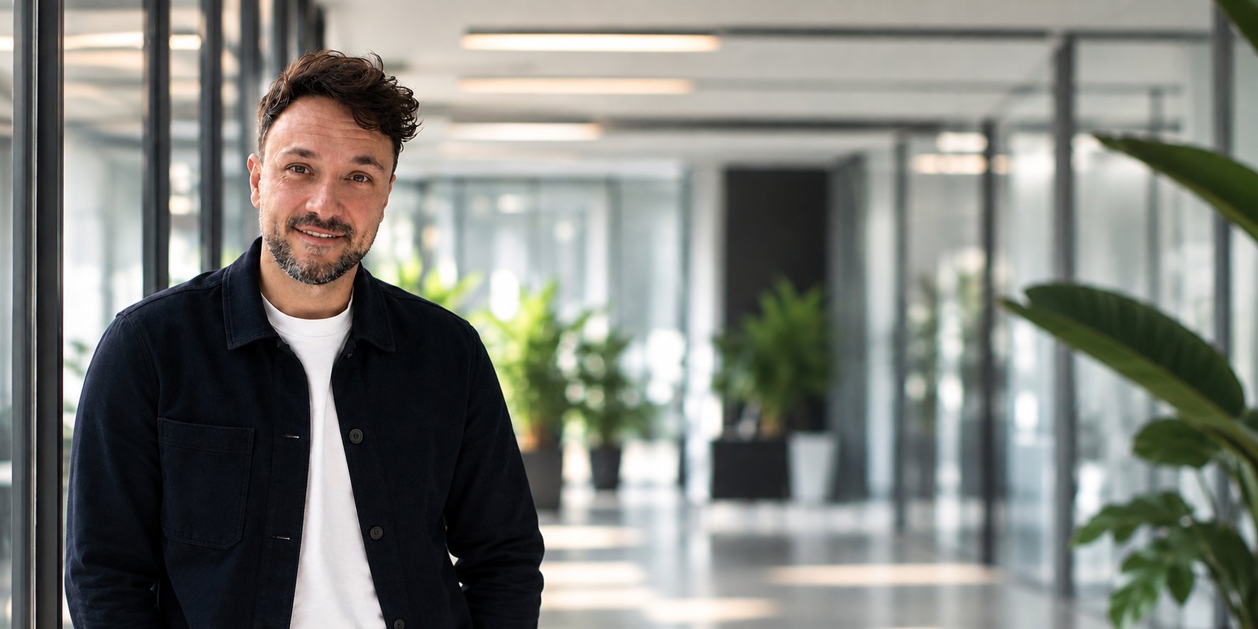 Yannick Wyzralek, Gründer von Kern Studio, lehnt an einer Glaswand in einem hellen Büro